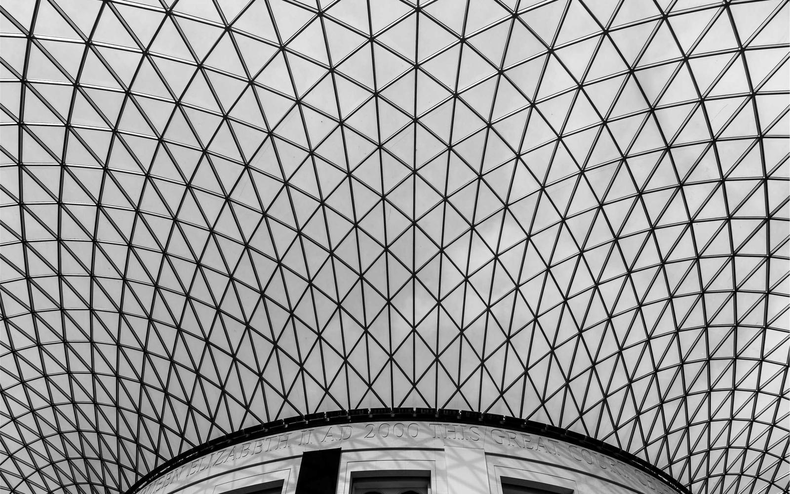A curving glass and steel lattice roof in black and white